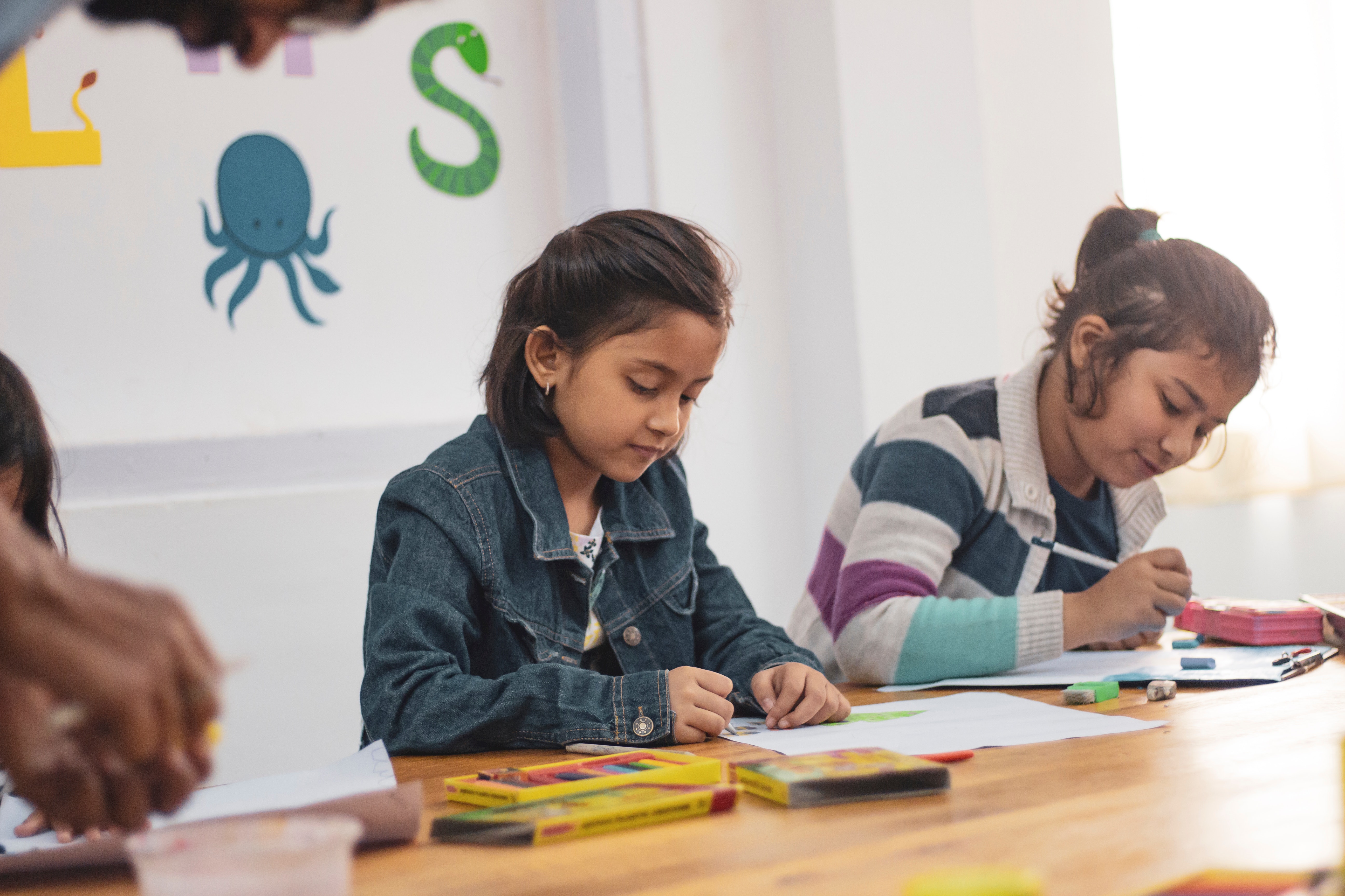 Two girls in school coloring at a table