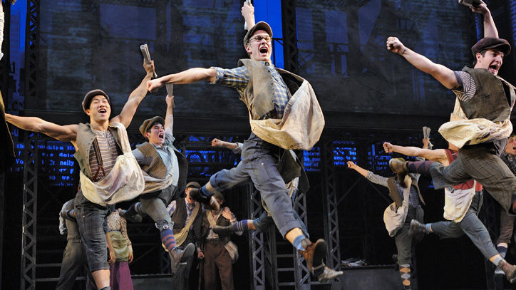 The Broadway cast of Disney's Newsies leaping through the air