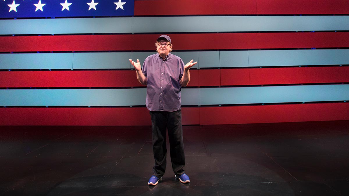 Michael Moore standing in front of the American flag