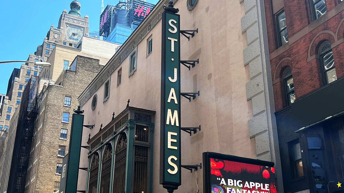 St. James Theatre writes 'St. James' in white all-caps vertical light lettering on a dark green background above the theatre entrance.
