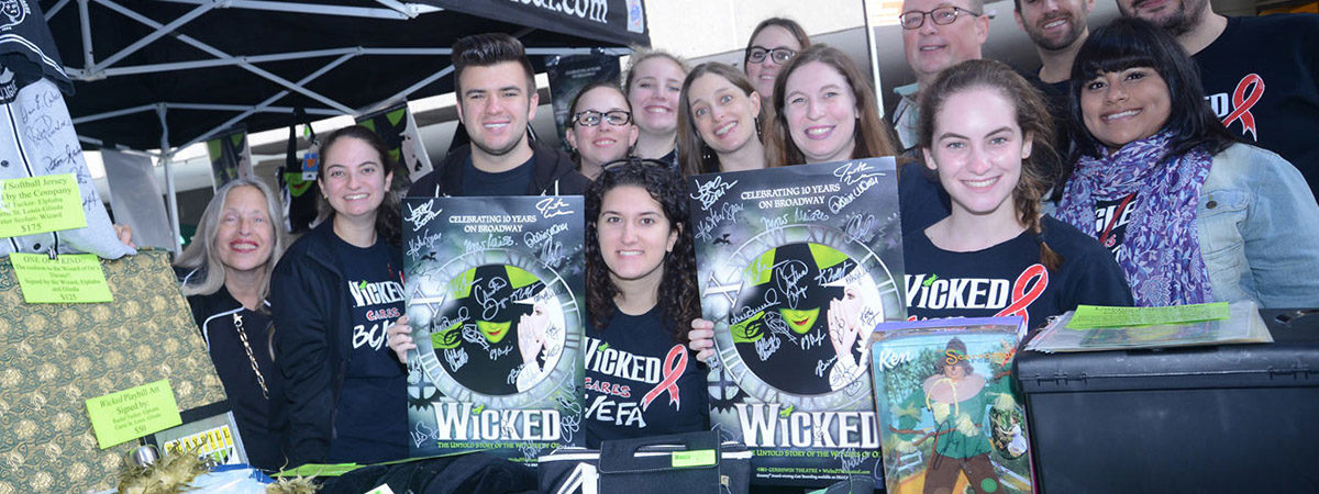 Fans of the Broadway musical Wicked holding up exclusive merchandise and surprises at the Broadway flea market