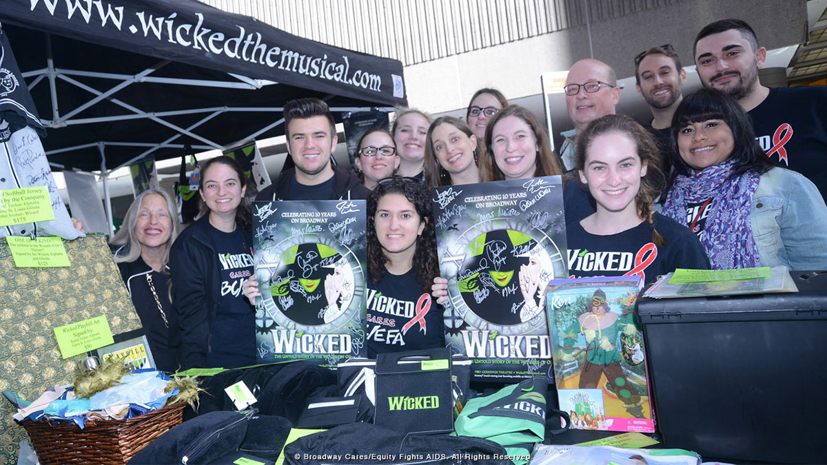 Fans of the Broadway musical Wicked holding up exclusive merchandise and surprises at the Broadway flea market