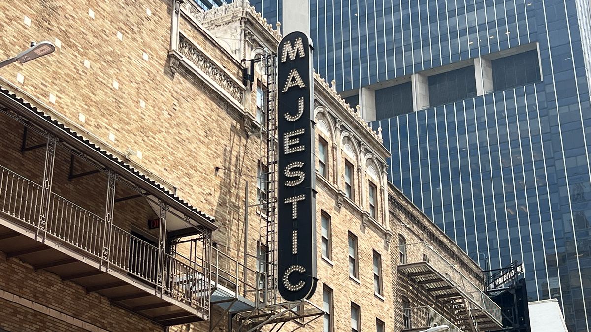 Majestic Theatre writes 'Majestic' in white all-caps vertical light lettering on a dark blue background above the theatre entrance.