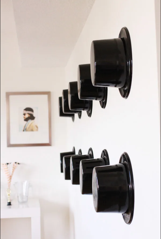 Plastic top hats attached to a wall in rows.