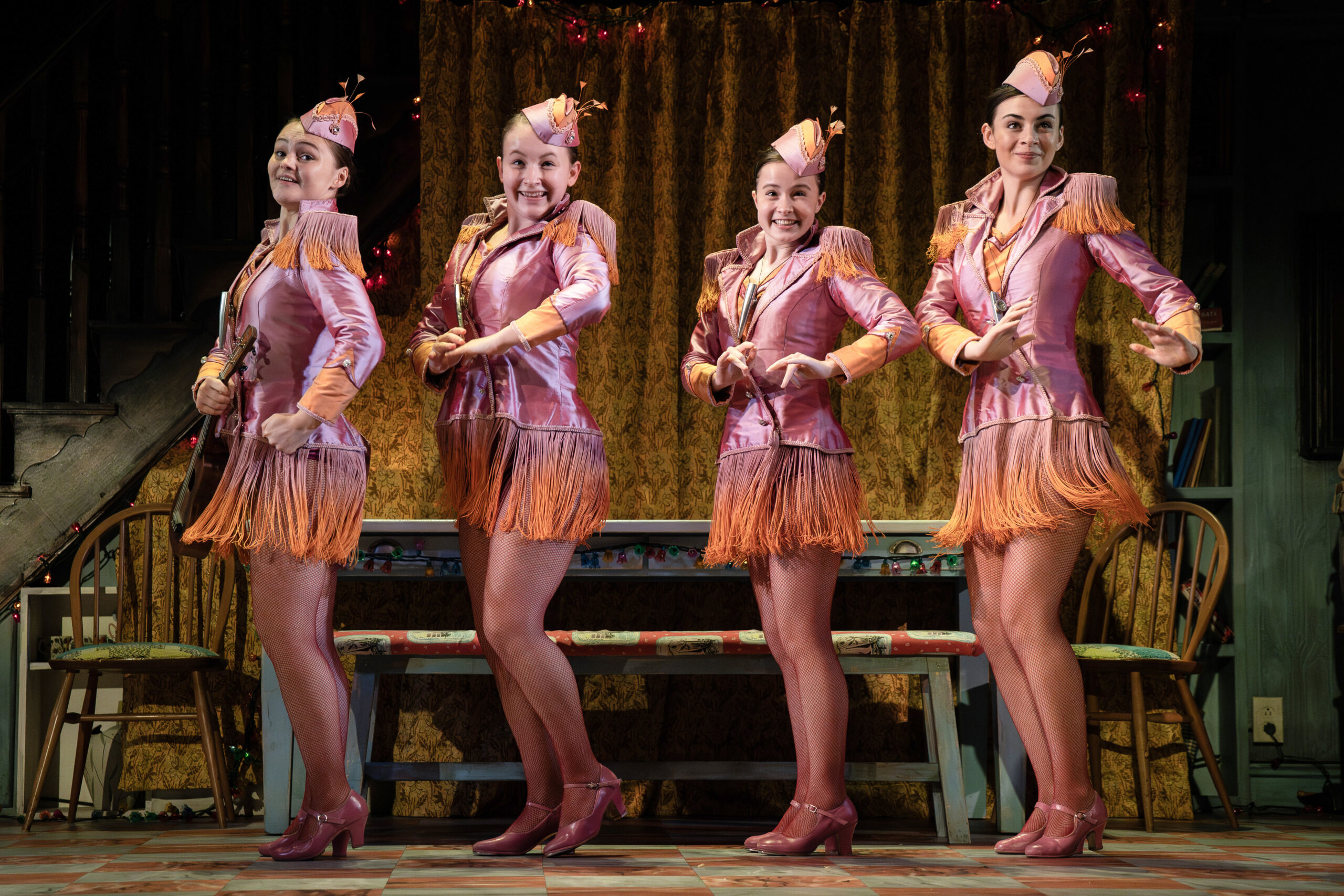 Four characters in bright pink and orange costumes in a single line formation