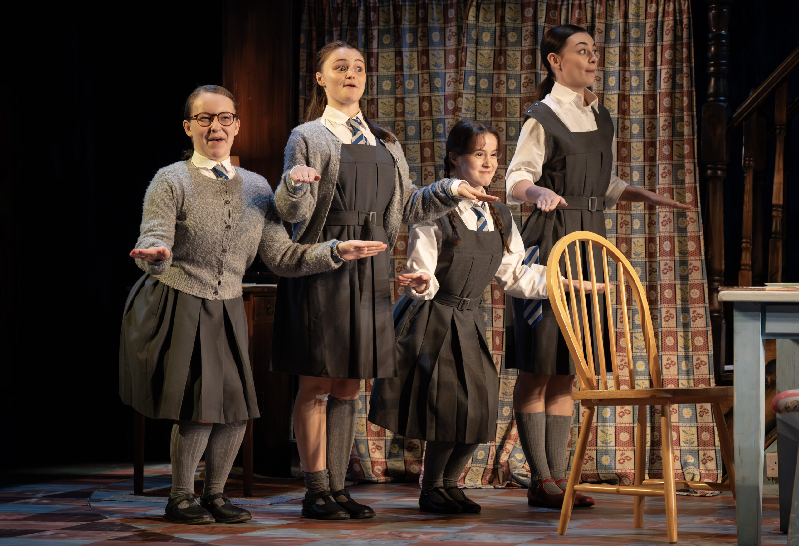 Four characters standing in a line formation in an alternating up down dance-like moment. 