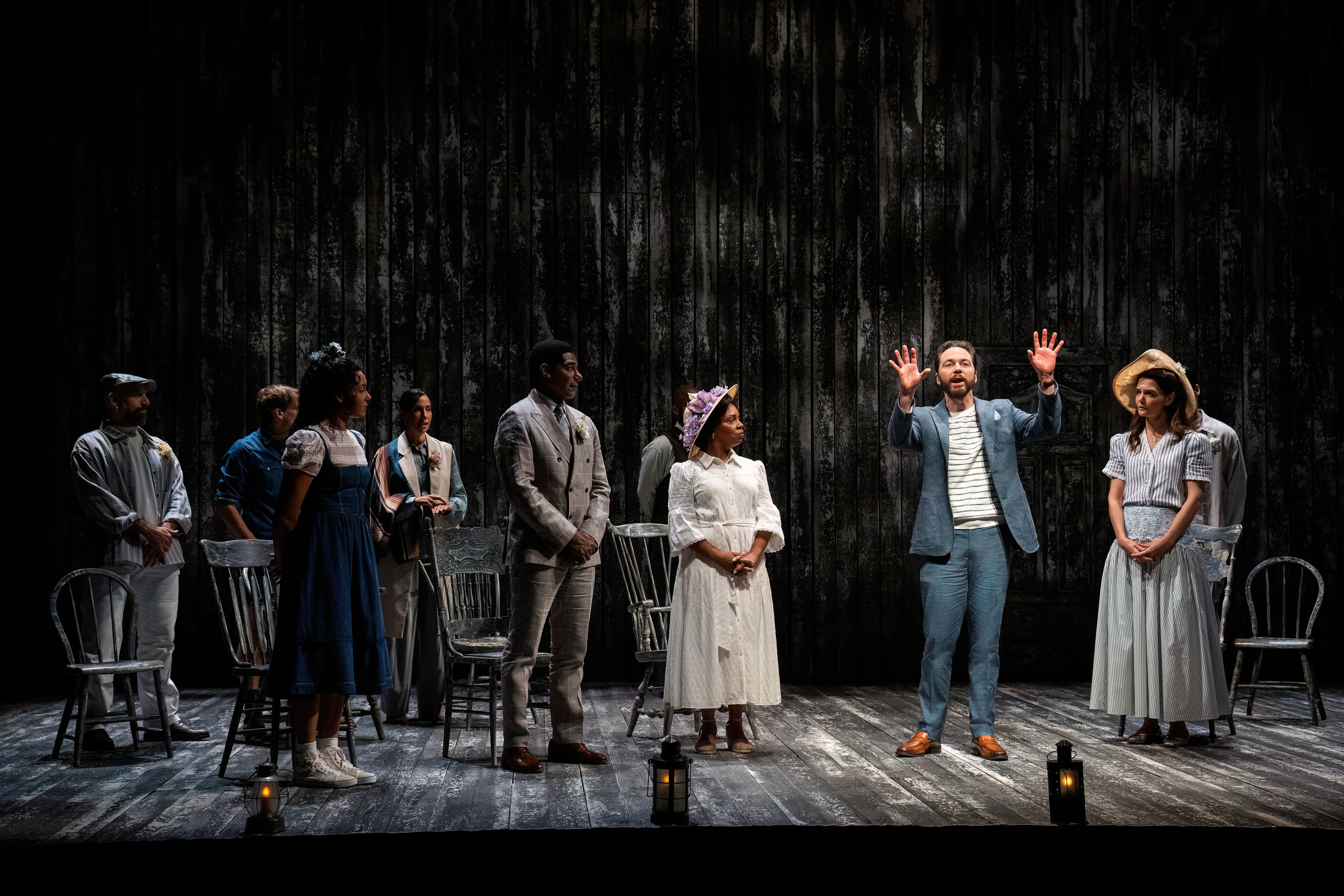 Characters on stage with one character under a brighter spotlight
