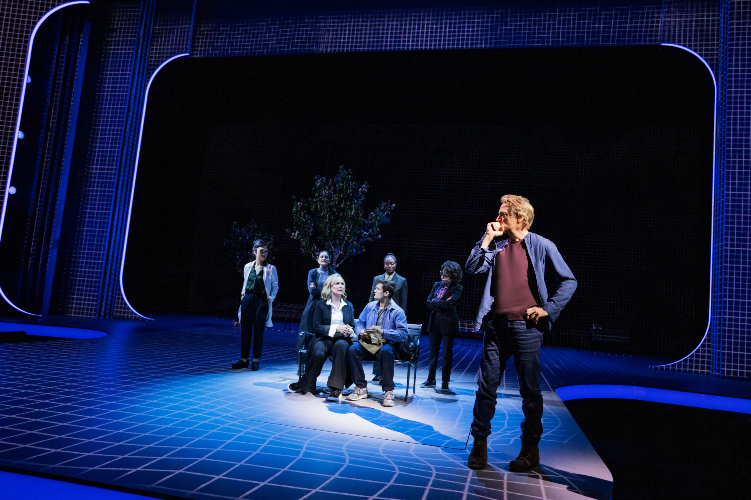 7 characters on stage with a warped grid on the stage and blue lighting.