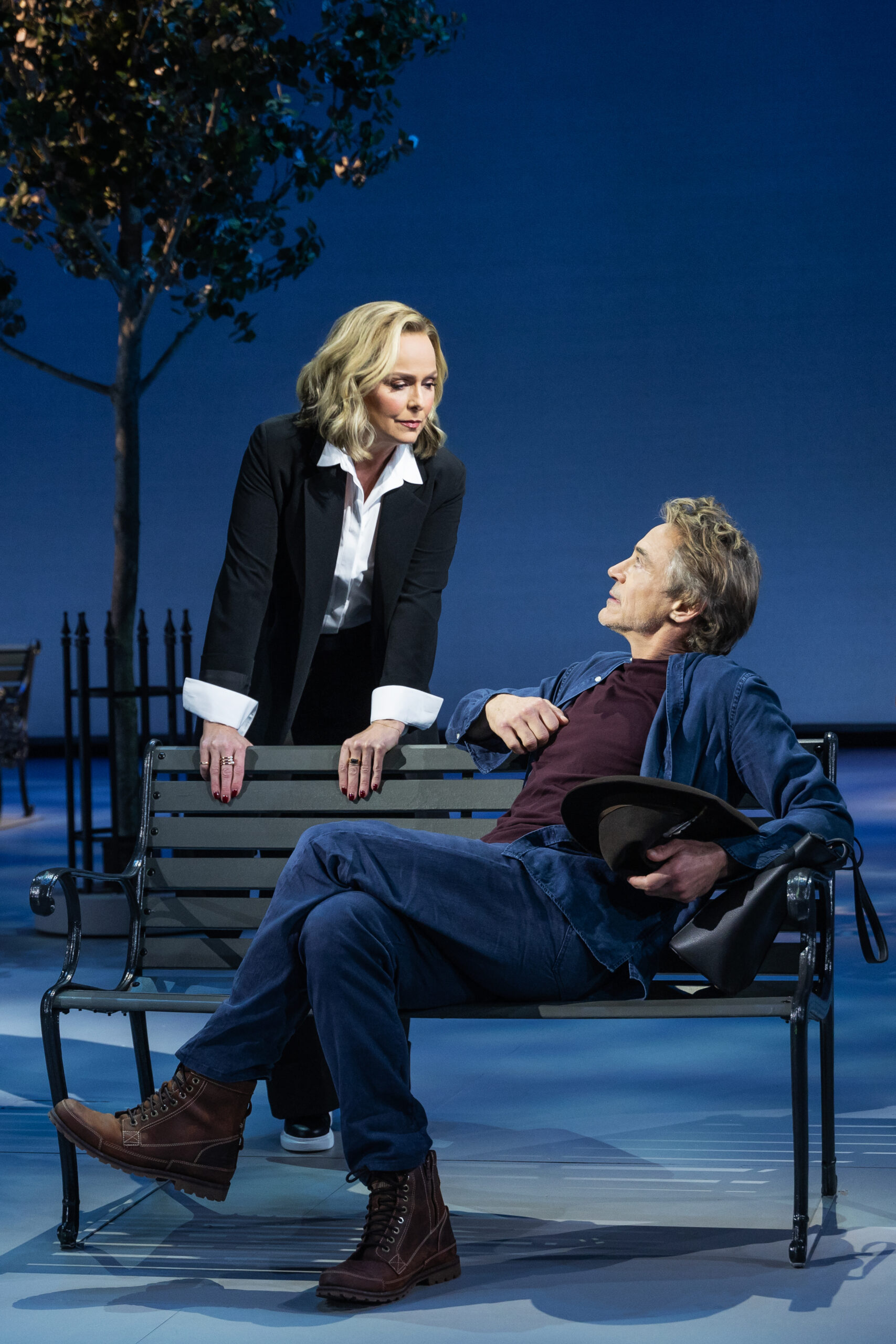 Two characters looking at each other, one character is sitting on a bench while the other is behind the bench leaning over