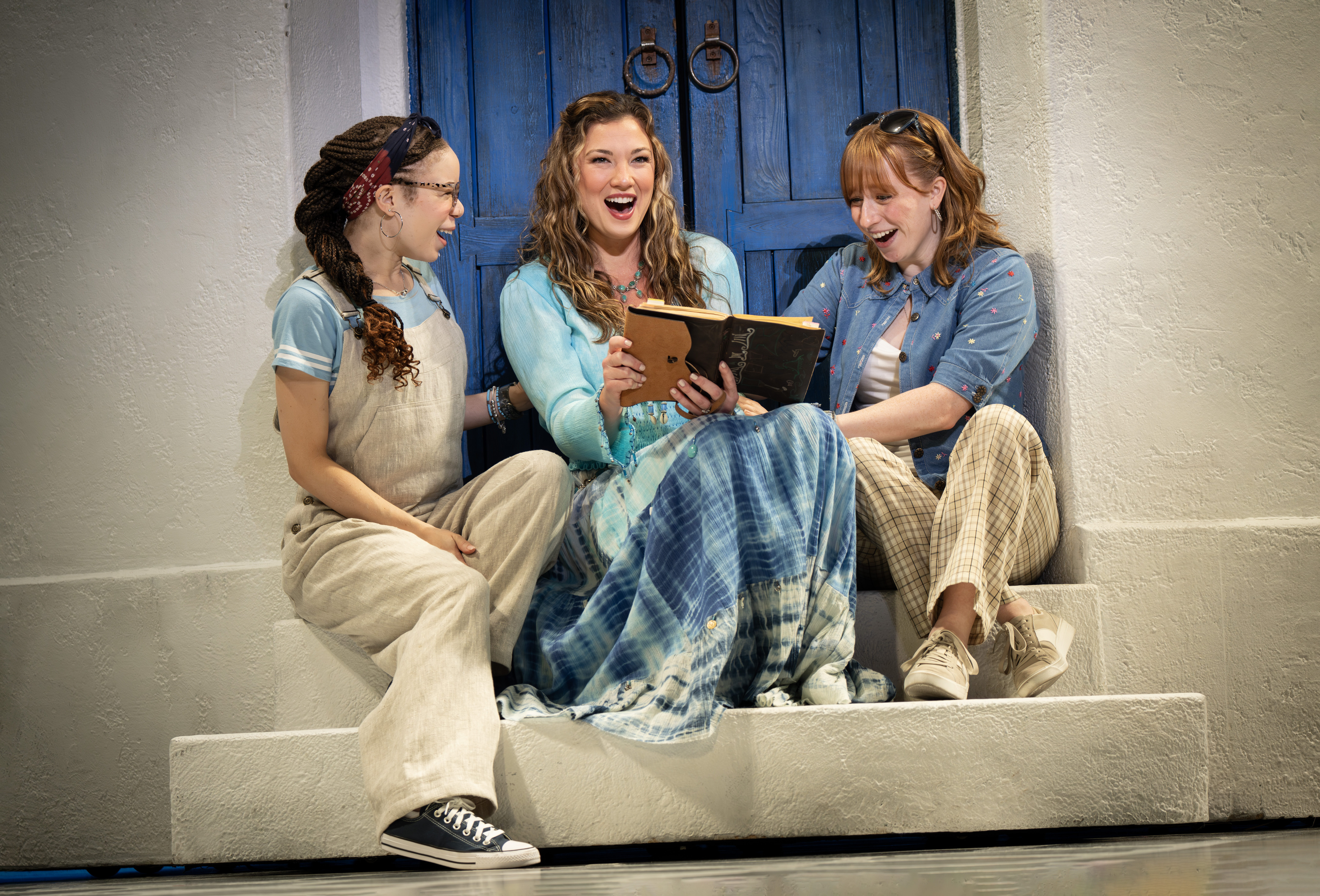 Lena Owens, Amy Weaver, and Haley Wright in MAMMA MIA! sittin on a step with a diary laughing.