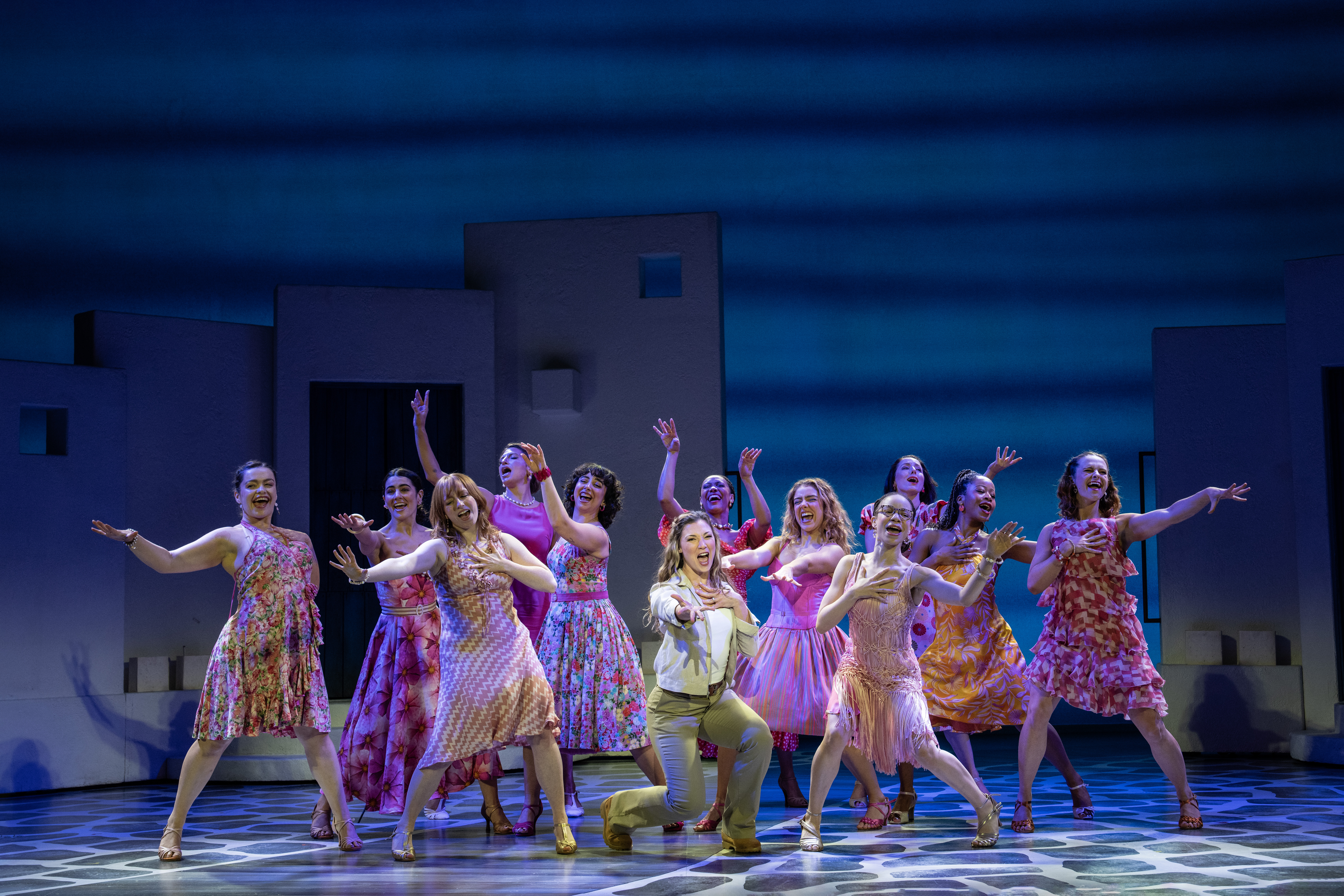 Amy Weaver and the Company of MAMMA MIA! spreading their arms out